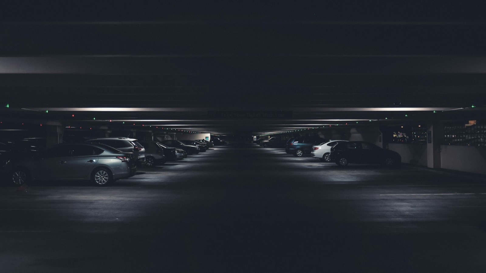Gece loş ışıklı kapalı otoparkta sıralı araçlar